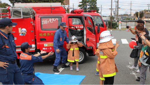 消防車の前で消防服を着た子どもたち