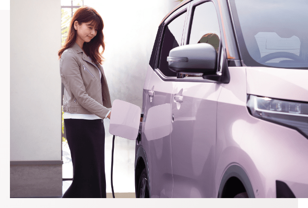 日産サクラを充電する女性の写真