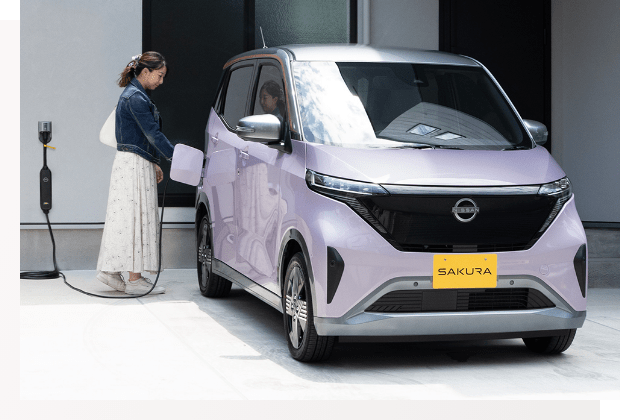 日産サクラを充電する女性の写真
